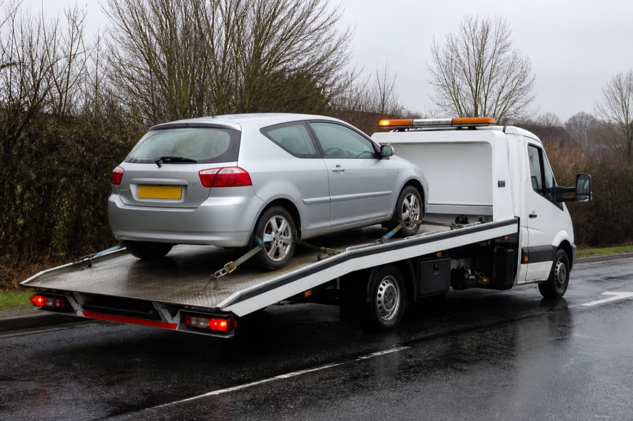 Flatbed recovery truck carrying a car on a slide deck